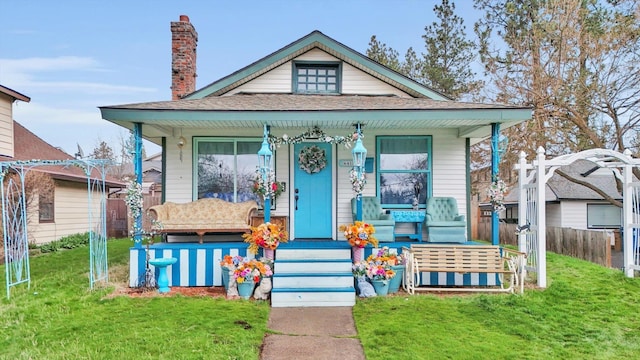 bungalow-style house with roof with shingles, fence, a front lawn, and covered porch