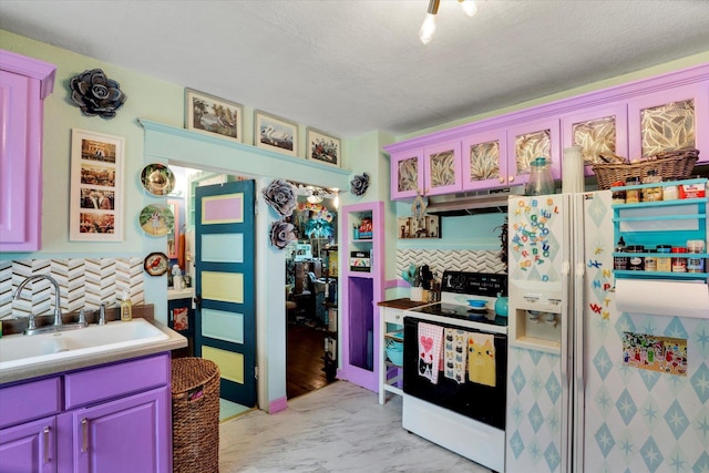 kitchen with white appliances, a textured ceiling, under cabinet range hood, marble finish floor, and a sink