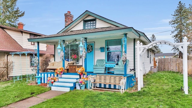 view of front of property with a front yard, a porch, and fence
