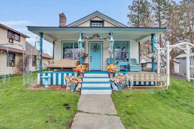 view of front of house with a porch, a front lawn, and a chimney