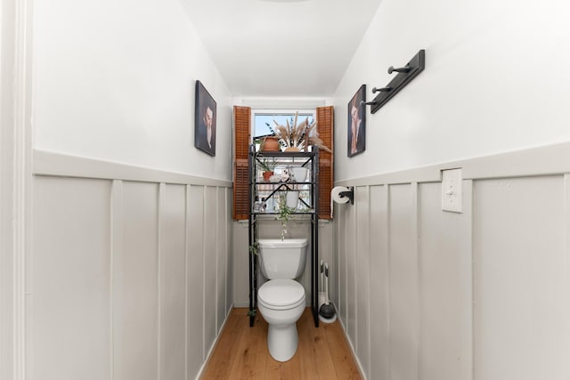bathroom with toilet, wood finished floors, and a wainscoted wall