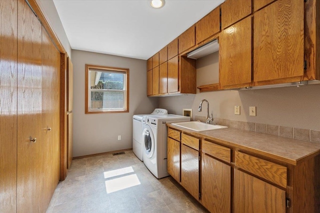 laundry area with visible vents, a sink, baseboards, cabinet space, and washer and clothes dryer