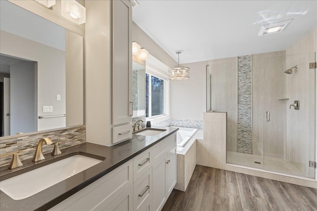 full bath featuring a shower stall, a garden tub, a sink, and wood finished floors