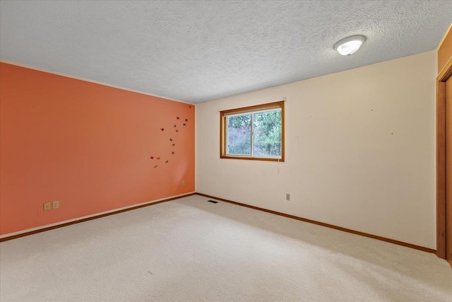 spare room with carpet floors, baseboards, visible vents, and a textured ceiling