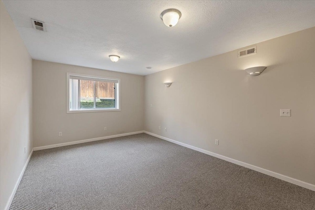 spare room featuring visible vents, a textured ceiling, and carpet floors