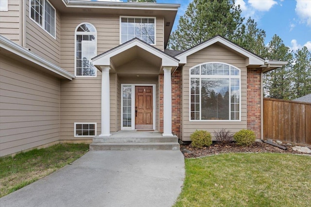 property entrance with a yard, brick siding, and fence