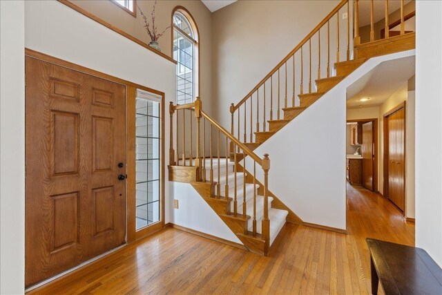 foyer entrance with wood-type flooring, stairway, and a high ceiling