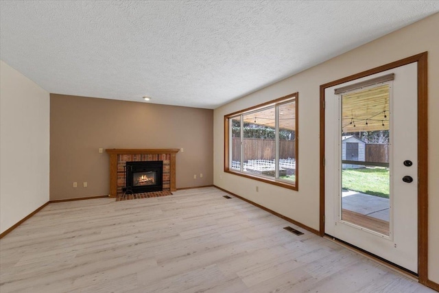unfurnished living room with light wood-style floors, a fireplace, and visible vents