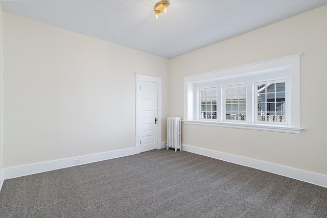 unfurnished room with radiator heating unit, dark colored carpet, and baseboards