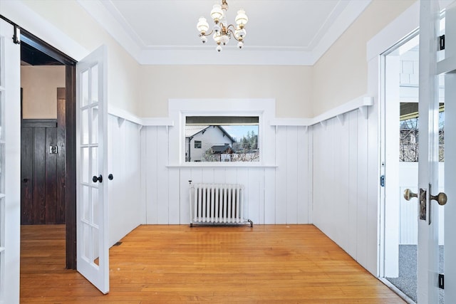 entryway featuring a chandelier, ornamental molding, radiator, and wood finished floors