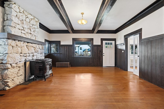 entrance foyer featuring a wainscoted wall, a wood stove, radiator, beam ceiling, and wood finished floors