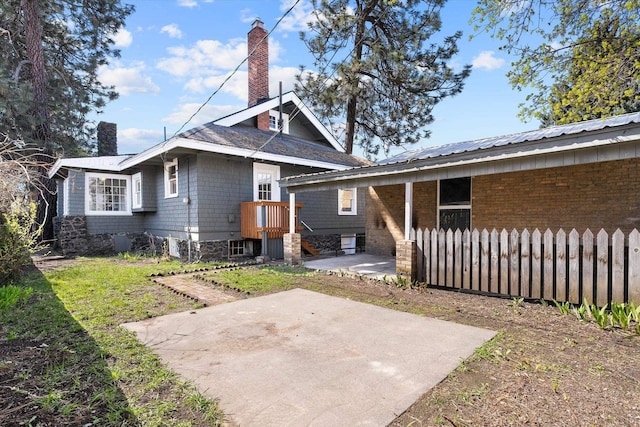 back of property featuring a chimney, a patio area, and fence