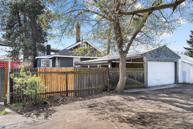 exterior space with fence, a detached garage, and dirt driveway