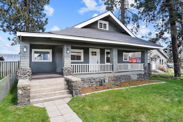 view of front of property with a shingled roof, fence, a front lawn, and covered porch