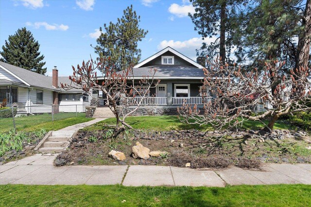 bungalow featuring a porch, fence, and a front lawn