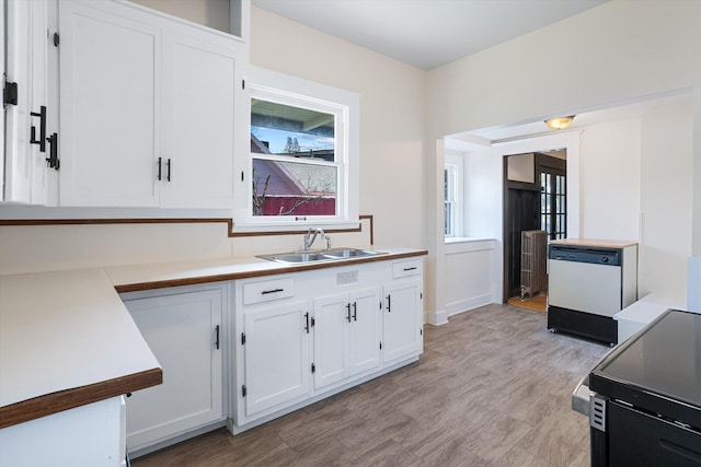 kitchen featuring white cabinets, white dishwasher, a sink, light countertops, and black electric range