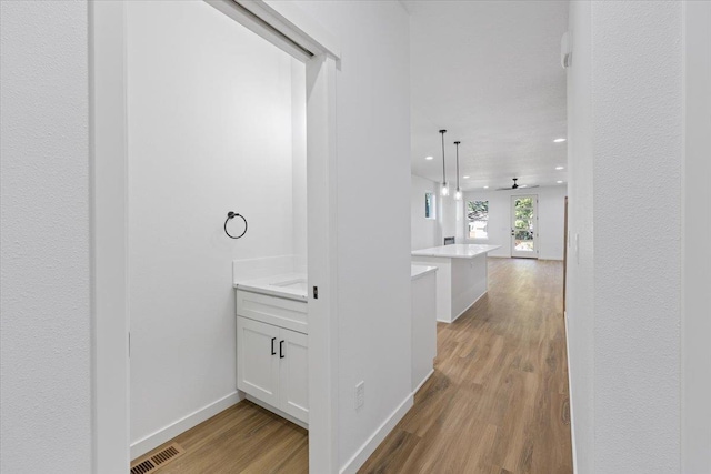 corridor featuring light wood-style floors, recessed lighting, and baseboards