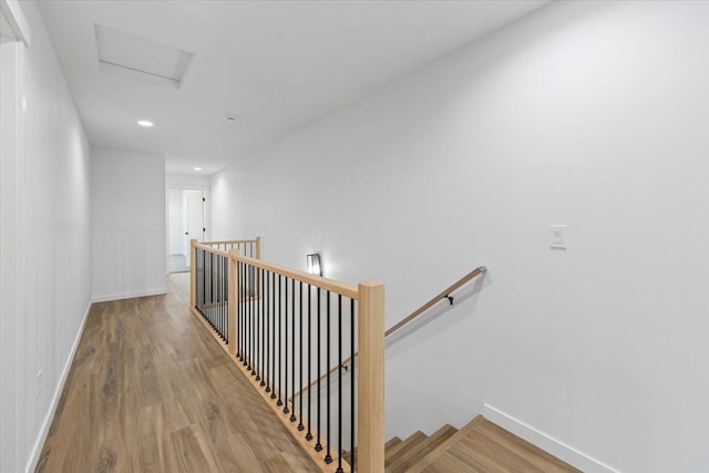 interior space featuring recessed lighting, attic access, baseboards, wood finished floors, and an upstairs landing