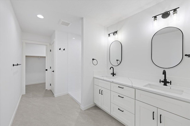 bathroom featuring double vanity, baseboards, and a sink