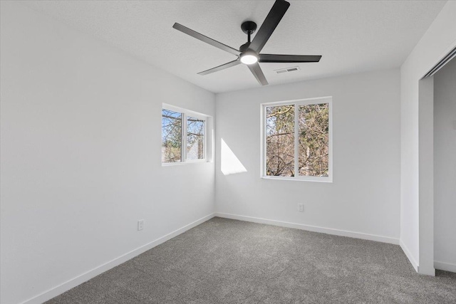 carpeted spare room with a ceiling fan and baseboards