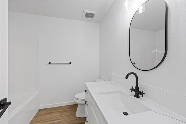 bathroom featuring toilet, wood finished floors, vanity, visible vents, and baseboards