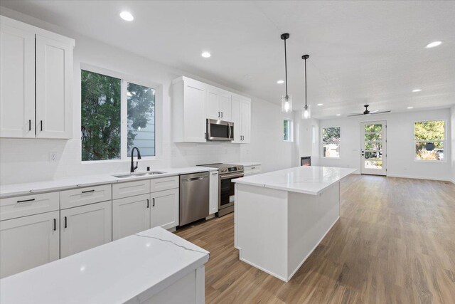 kitchen featuring appliances with stainless steel finishes, a sink, open floor plan, recessed lighting, and backsplash
