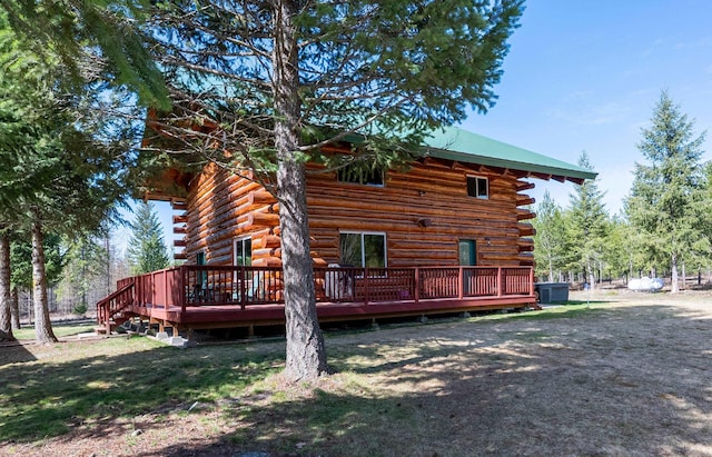 rear view of house with cooling unit, a deck, metal roof, and log siding