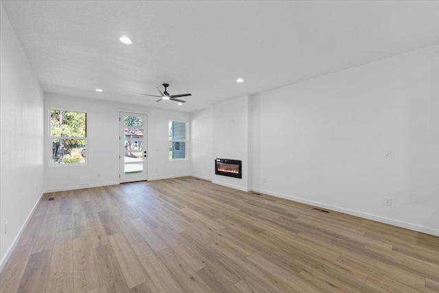 1920 E 37th Ave, Spokane, WA 99203 - unfurnished living room featuring baseboards, recessed lighting, a glass covered fireplace, and light wood-type flooring