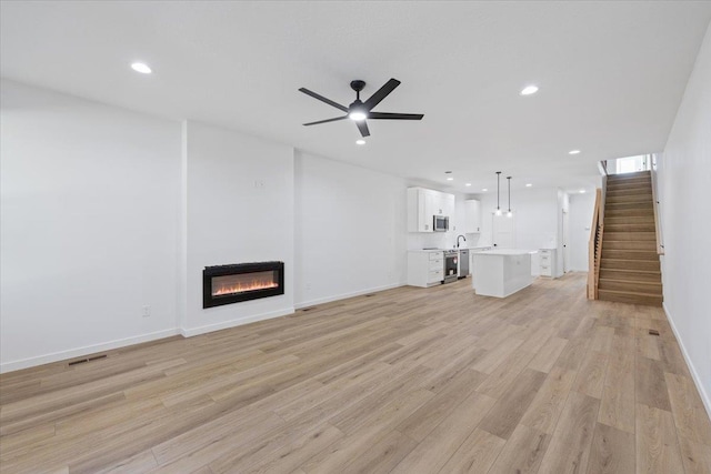1920 E 37th Ave, Spokane, WA 99203 - unfurnished living room featuring stairs, visible vents, recessed lighting, a glass covered fireplace, and light wood-style floors