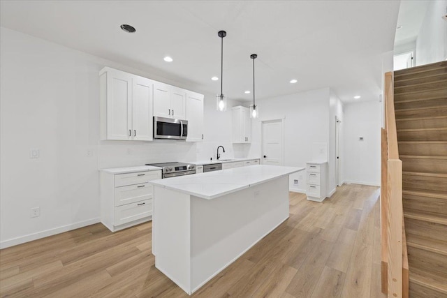 1920 E 37th Ave, Spokane, WA 99203 - kitchen with recessed lighting, light wood finished floors, white cabinets, and appliances with stainless steel finishes