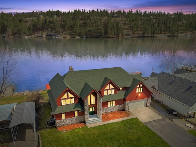 view of front of house with a water view, a front lawn, stone siding, and driveway