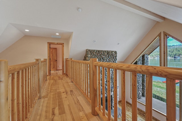 hallway with an upstairs landing, visible vents, light wood-style flooring, and vaulted ceiling with beams