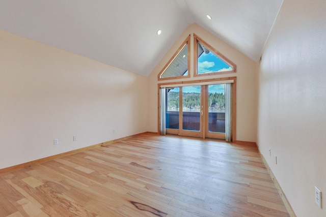 spare room with baseboards, high vaulted ceiling, and light wood-style floors