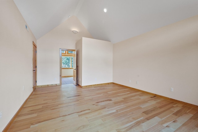 empty room with light wood-style flooring, high vaulted ceiling, baseboards, and visible vents
