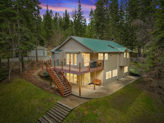 rear view of house featuring a lawn, a patio area, metal roof, stairs, and a deck