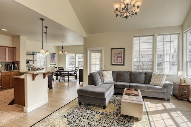 living area with a chandelier, light wood-style floors, and lofted ceiling