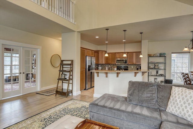 living room with a towering ceiling, light wood-style flooring, and baseboards