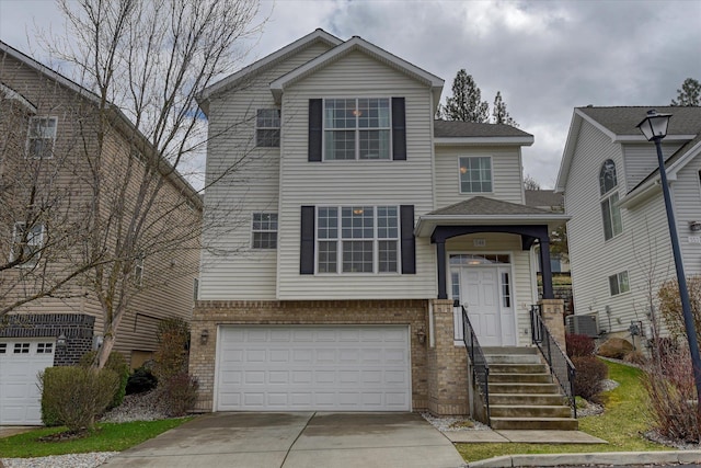 view of front of property with brick siding, an attached garage, central air condition unit, and concrete driveway