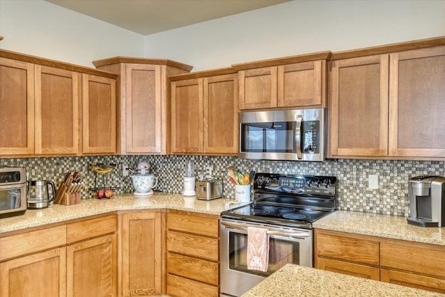 kitchen with brown cabinetry, light stone countertops, decorative backsplash, and appliances with stainless steel finishes