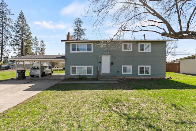 raised ranch with a carport, a chimney, a front yard, and concrete driveway
