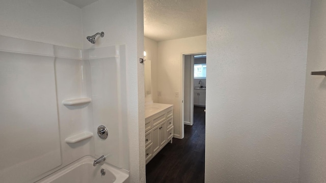 full bathroom featuring vanity, a textured ceiling, wood finished floors, and shower / washtub combination