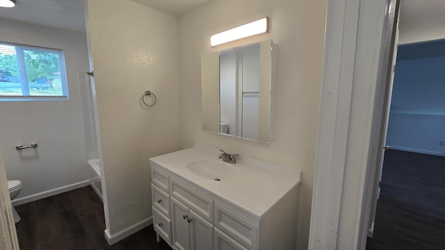 full bath with baseboards, toilet, a textured wall, vanity, and wood finished floors