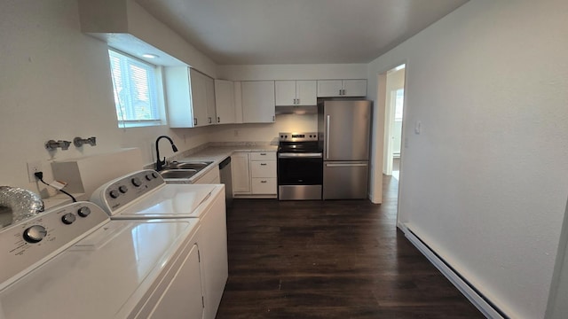 kitchen featuring appliances with stainless steel finishes, a baseboard heating unit, independent washer and dryer, dark wood finished floors, and a sink