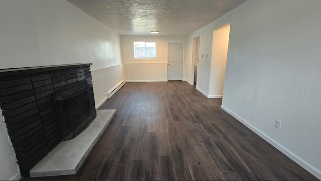 unfurnished living room featuring a textured ceiling, a fireplace with raised hearth, baseboard heating, baseboards, and dark wood-style floors