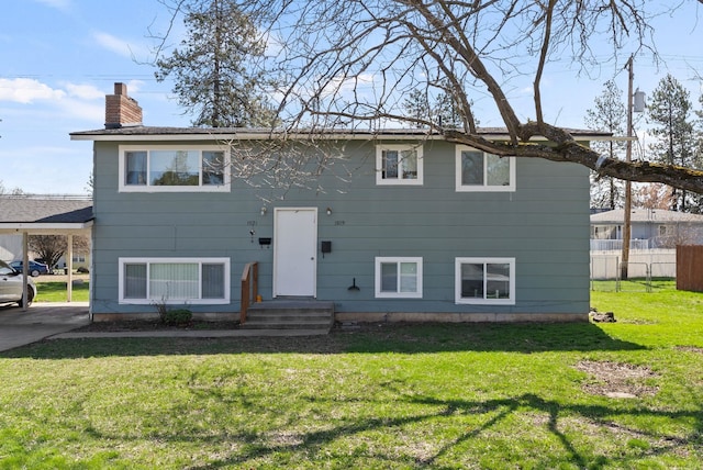 raised ranch featuring a front yard, fence, and a chimney