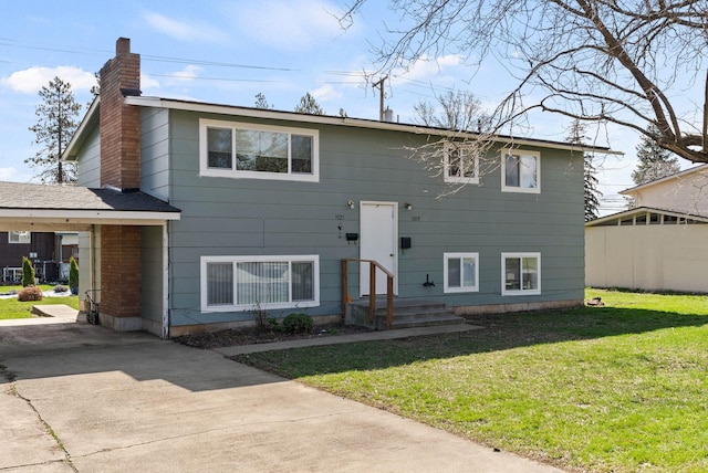 bi-level home featuring driveway, a chimney, and a front lawn