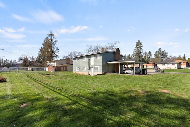 rear view of property featuring a chimney, fence, and a lawn