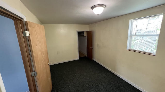 hallway with baseboards and dark colored carpet