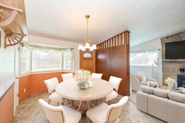 dining room with a chandelier, a fireplace, and a healthy amount of sunlight