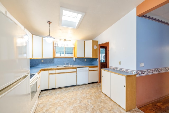 kitchen with white appliances, white cabinets, a skylight, a sink, and hanging light fixtures